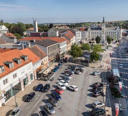 Luftbild des Hauptplatzes Mistelbach, mittig die Parkfläche, rechts und links die Geschäfte, im Vordergrund das Rathaus