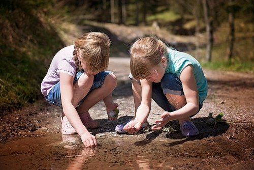 Zwei Kinder spielen in einer Pfütze im Wald