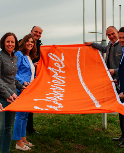 Pressefoto Station 1 Sulz, Vertreter:innen halten Weinviertel Flagge und stehen Links und Rechts davon