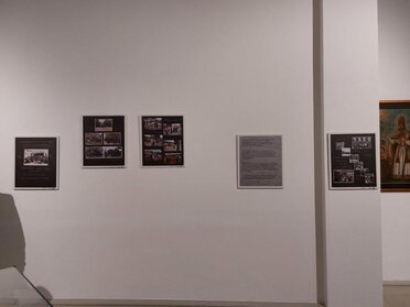 Eröffnung der Ausstellung "325 Jahre Hauerzunft Mistelbach". Zu sehen ist eine weiße Wand auf der schwarze Ausstellungstafeln zu sehen sind. Auf den Ausstellungstafeln werden alte Fotos der Hauerzunft Mistelbach gezeigt.