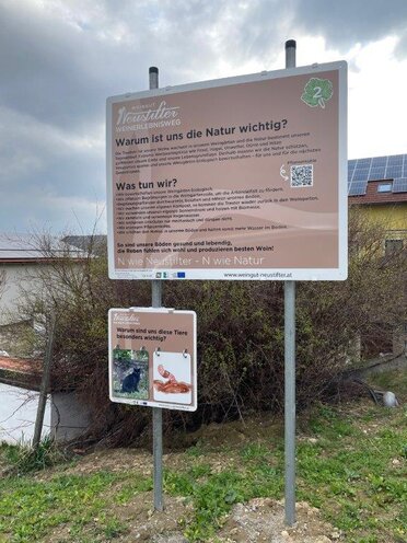 Eine Infotafel warum die Natur für das Weingut Neustifter wichtig ist. Darunter ist eine kleine Tafel mit Klappbildern, warum eine Katze und ein Regenwurm besonders wichtig ist.