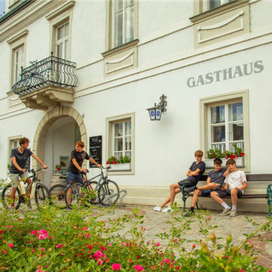 Kinder kommen mit einem Fahrrad und treffen Freunde vor dem Rathhaus