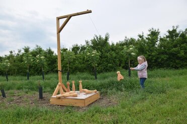 Ein kleines Mädchen spielt mit einer Holzbien kegeln.