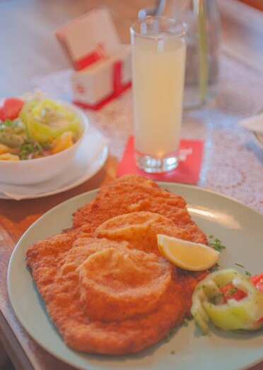 Mittagsmenü Wiener Schnitzel mit einer Zitrone als Deko und mit Salat als Beilage 