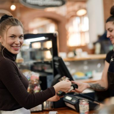 Junge Frau zahl mit Karte im Kaffeehaus