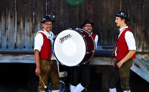 3 Musikanten vor einem Holzstadel