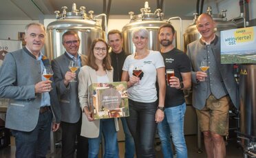 Das Organisationsteam der Sommer Genusstour im Weinviertel beim Betrieb Hopfius. Im Hintergrund sind Bierkessel zu sehen.