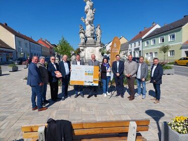 Bürgermeisterinnen, Bürgermeister sowie Vertreter von Weinviertel Tourismus am Hauptplatz von Ernstbrunn bei der Eröffnung der Kreuttalradrunde. In der Hand halten sie die Übersichtstafel der Kreuttalradrunde.
