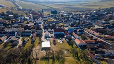Luftaufnahme des Ortes Pillichsdorf. Im Vordergrund ist die Gemeindewiese mit dem Gasthaus zu sehen, im Hintergrund die Kirche.