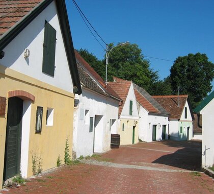 Kellergasse in Falkenstein, bunten Kellerhäuser rechts und links der rot gepflasterten Straße.