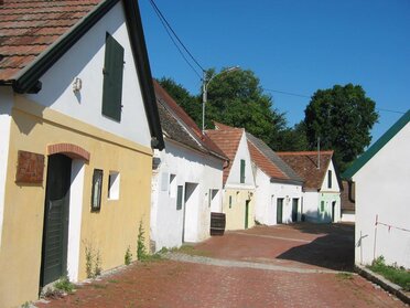 Kellergasse in Falkenstein, bunten Kellerhäuser rechts und links der rot gepflasterten Straße.