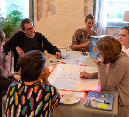 Vier Menschen sitzen an einem Tisch.Besprechen
