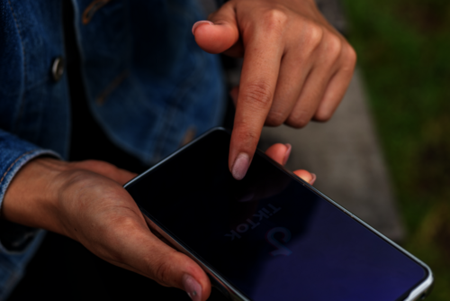 Frau mit Handy klickt auf TikTok