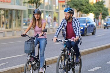 Auf dem Symbolbild, dass das Alltagsradfahren im Weinviertel darstellen sollen, ist eine Frau und ein Mann zu sehen, welche mit einem Fahrrad in einer Stadt fahren. Beide tragen einen Helm und sind in Jeans und T-Shirt unterwegs. Sie fahren auf einer Radspur, im Hintergrund ist ein Auto auf der danebenliegenden Straße zu sehen.
